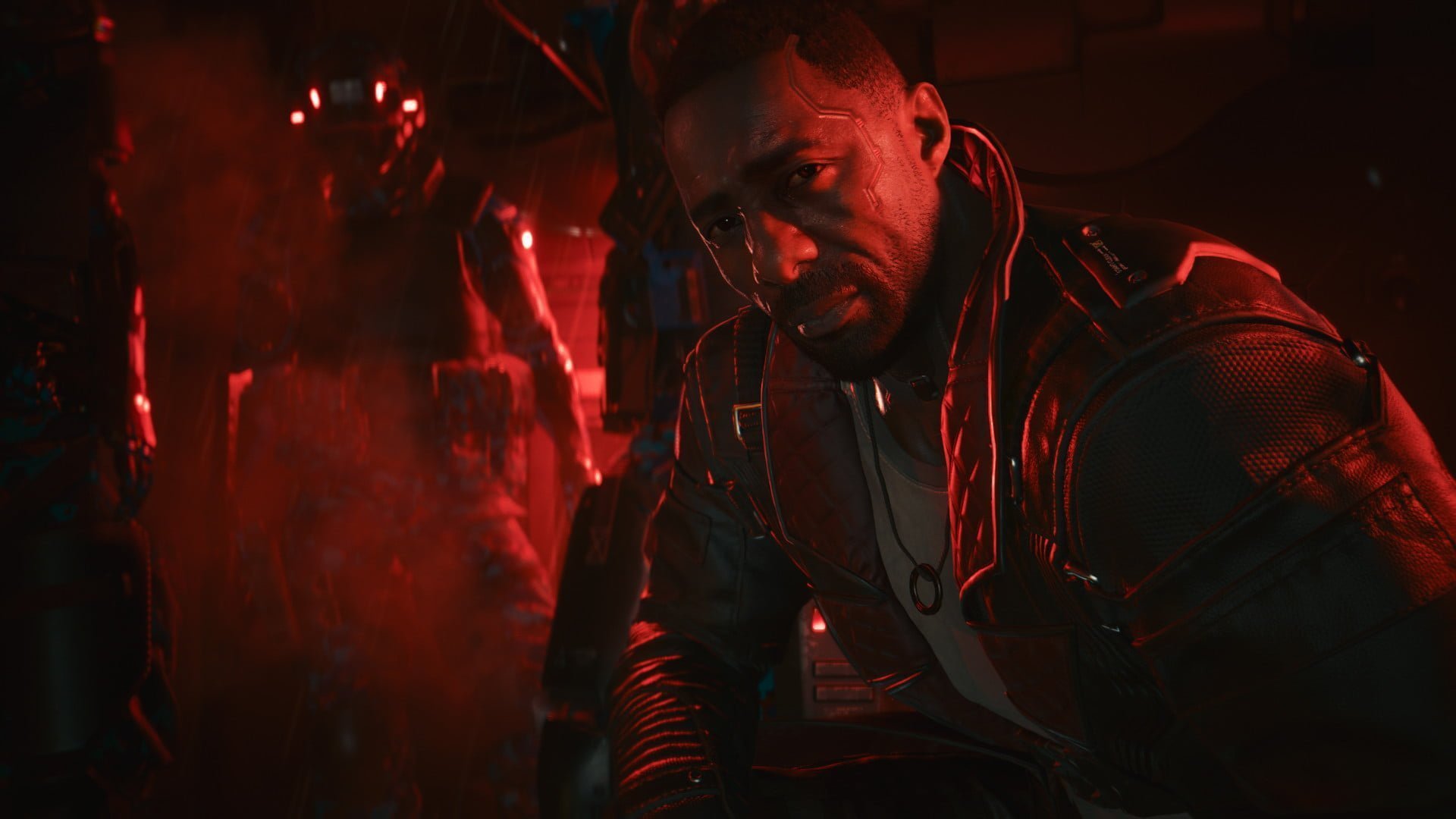 A character played by Idris Elba sitting in a red-lighted room.