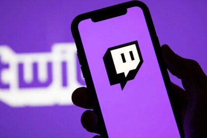 Person holding a phone with the Twitch logo displayed on it.